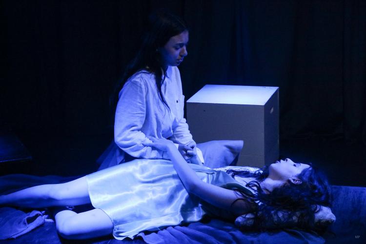 Cena de “The Stratford Company", em que se vê uma personagem deitada e outra em gesto de assistência