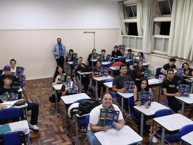sala de aula com estudantes com livros de didático em mãos