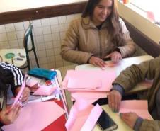 Um grupo de alunas trabalha na preparação de origamis, que serão usados como acessórios pendurados nos guarda-chuvas e nas sobrinhas já concluídas para a ocasião do evento surpresa.