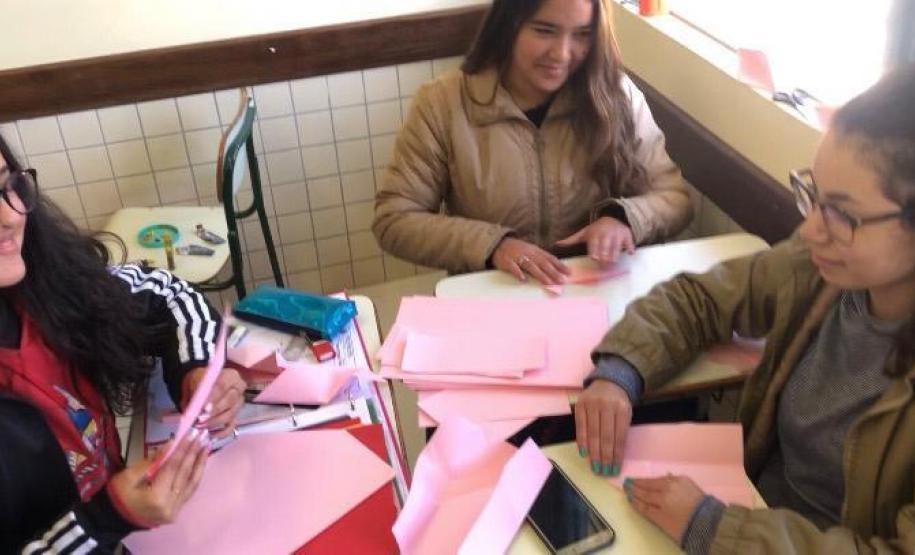 Um grupo de alunas trabalha na preparação de origamis, que serão usados como acessórios pendurados nos guarda-chuvas e nas sobrinhas já concluídas para a ocasião do evento surpresa.