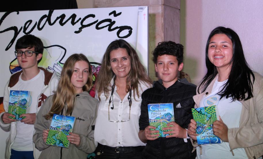 A cerimônia na noite desta quinta-feira (7) reuniu, no hall de entrada do Colégio Estadual do Paraná (CEP), estudantes, professores, poetas e convidados para a entrega do livro Sedução Poética 2019. O exemplar representa a conclusão de mais uma edição do projeto de linguagem coordenado pelo setor de Língua Portuguesa do Colégio, com objetivos de envolver e incentivar a Comunidade Escolar a produzir, declamar e publicar textos e ilustrações relacionados com a poesia.